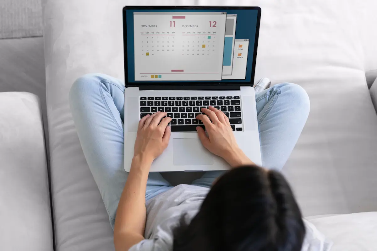 Pessoa consulta calendário no notebook para planejar folgas e períodos de descanso nos próximos feriados nacionais de 2026.