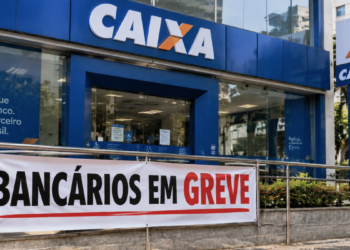 Fachada de agência da Caixa Econômica Federal com faixa indicando greve dos bancários durante paralisação dos funcionários.