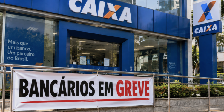 Fachada de agência da Caixa Econômica Federal com faixa indicando greve dos bancários durante paralisação dos funcionários.