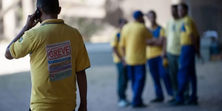 Trabalhador dos Correios usando uniforme durante greve nacional da categoria com paralisação das atividades.