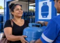 Mulher recebe botijão de gás em revenda participante do programa Gás do Povo