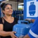 Mulher recebe botijão de gás em revenda participante do programa Gás do Povo