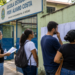 Candidatos consultam listas em frente a uma escola antes da prova do concurso Sedes DF.