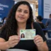 Mulher segura a nova Carteira de Identidade Nacional durante mutirão para emissão do documento em shopping sem agendamento.