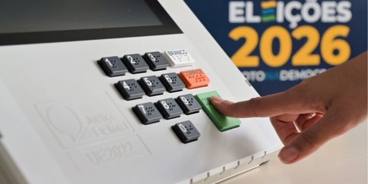 Dedo pressionando a tecla verde de confirmação da urna eletrônica ao lado da marca Eleições 2026
