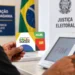 Pessoa segurando cartão do Bolsa Família em seção eleitoral com urna eletrônica ao fundo