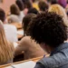 Estudantes sentados em carteiras durante aplicação de prova em sala de aula.
