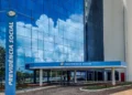 Fachada envidraçada do edifício sede da Previdência Social, com totem de identificação na entrada, órgão responsável pelo concurso do INSS.
