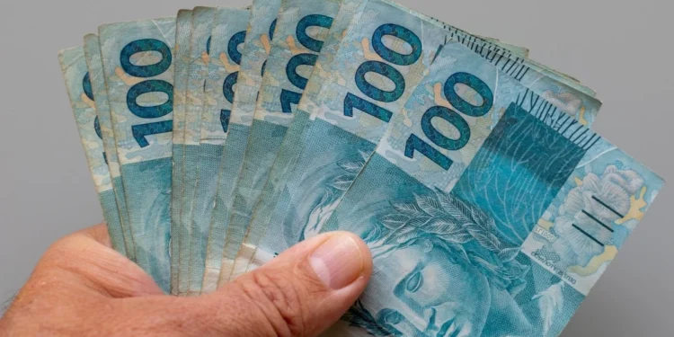 Mão segura cédulas de R$ 100 em referência aos recursos previstos no Projeto de Lei Orçamentária de 2027.