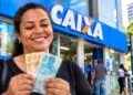 Mulher segurando notas de real em frente a uma agência da Caixa representando os pagamentos do ressarcimento do PIS/Pasep em 2026