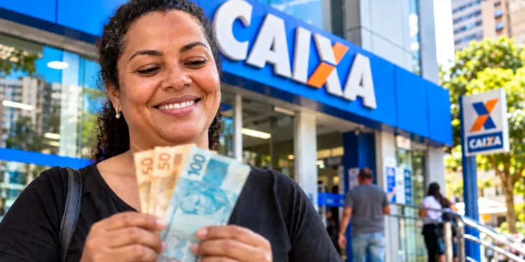 Mulher segurando notas de real em frente a uma agência da Caixa representando os pagamentos do ressarcimento do PIS/Pasep em 2026