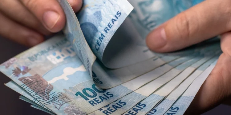Notas de real sendo contadas representam o pagamento do salário até o quinto dia útil de setembro.