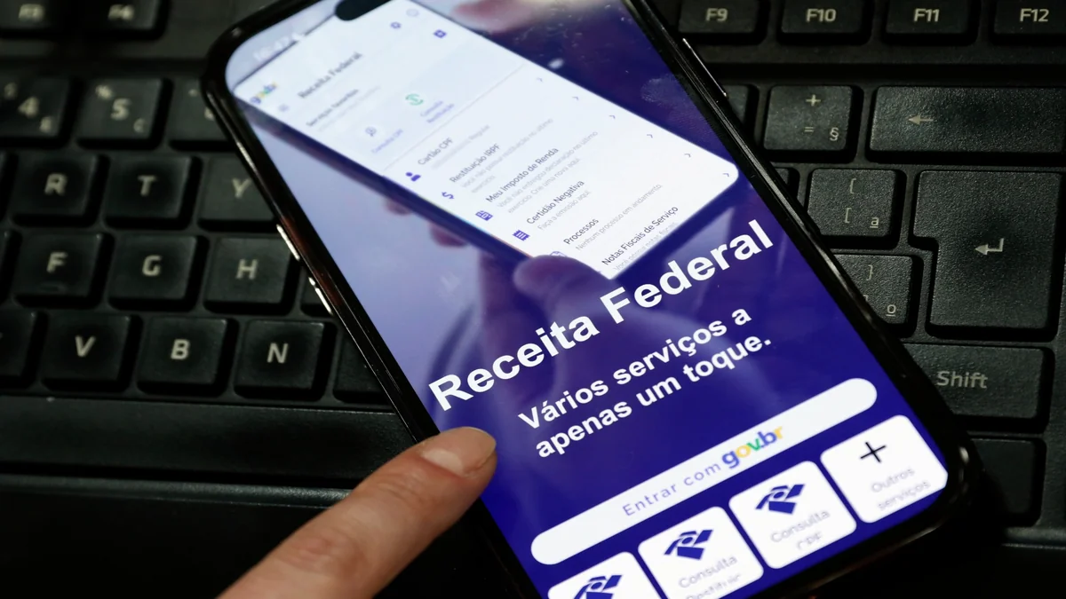 Aplicativo da Receita Federal exibido em celular representa a consulta e o pagamento do lote residual de restituição do IR 2026.