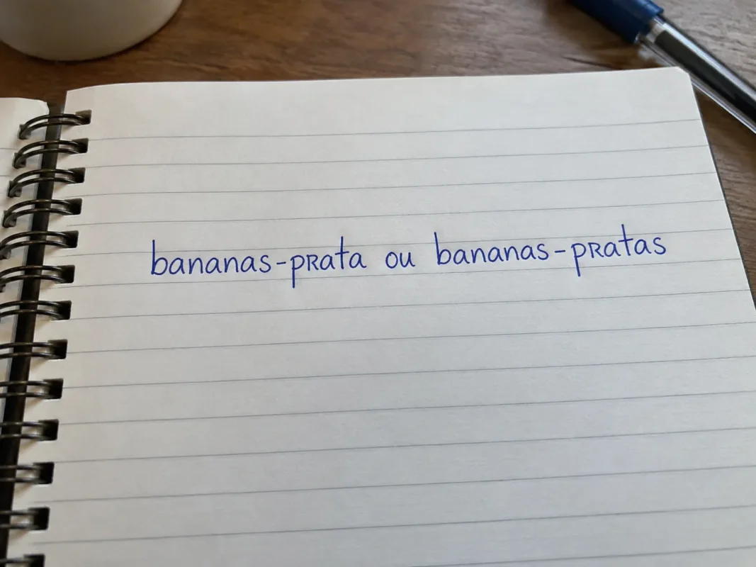 Exemplo visual do plural de banana-prata com as formas bananas-prata e bananas-pratas escritas em um caderno