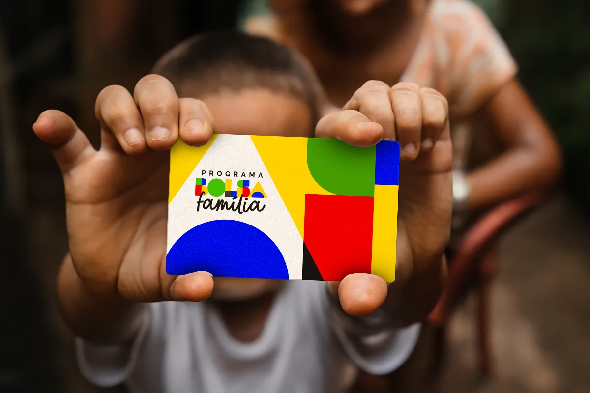 Criança segura cartão do Bolsa Família, representando as famílias que podem ter direito ao benefício.
