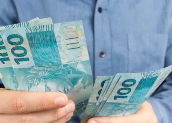 Trabalhador contando cédulas de R$ 100, representando o saque-aniversário do FGTS para nascidos em setembro.