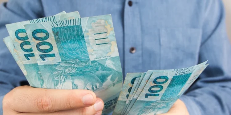 Trabalhador contando cédulas de R$ 100, representando o saque-aniversário do FGTS para nascidos em setembro.