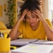 Concurseira estudando em casa, com expressão de preocupação, representando a importância da saúde mental durante a preparação para concursos públicos.