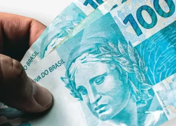 Notas de R$ 100 em mãos de segurado representam os valores atrasados do INSS liberados pela Justiça para beneficiários.