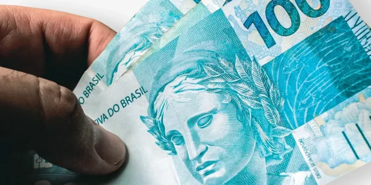 Notas de R$ 100 em mãos de segurado representam os valores atrasados do INSS liberados pela Justiça para beneficiários.